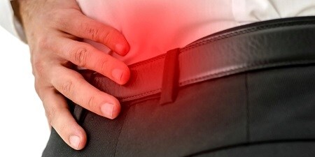 Mężczyzna trzymający się za dolną część pleców
