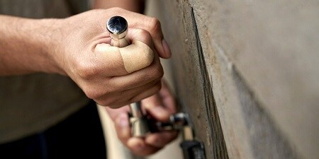 Dłonie remontującego mężczyzny z plastrem na palcu
