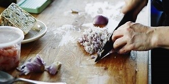 Osoba krojąca na desce cebulę
